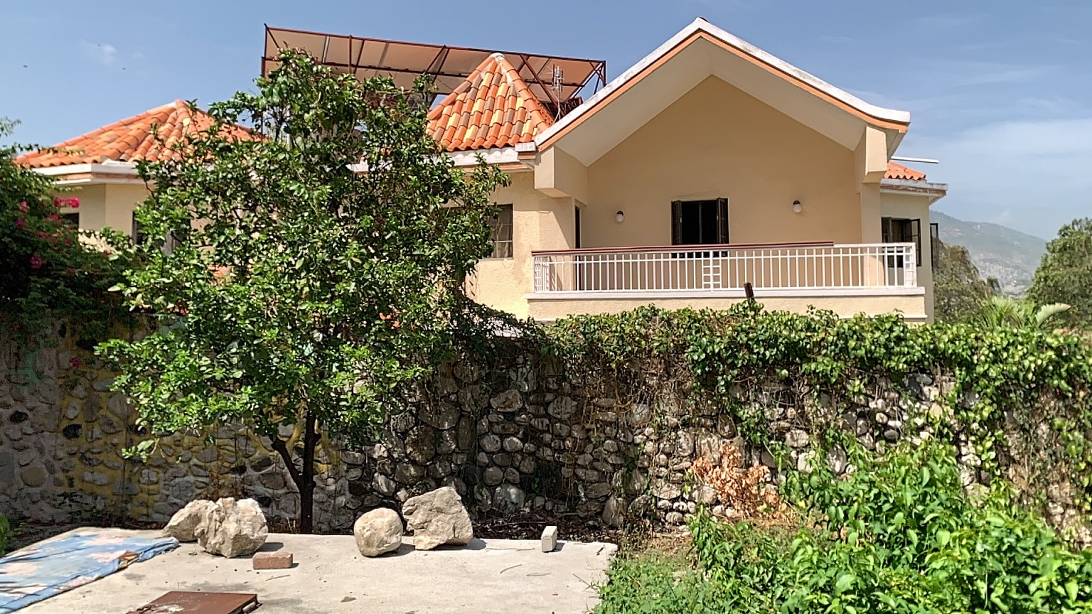 Palace-Style Villa for Sale, Vivy Mitchell, Petion-Ville, Haiti – House or Home has 6 Spacious Bedrooms, 5 1/2 Bathrooms, Multiple Grand Living & Dining Rooms, Majestic Kitchen, Whirlpool Jacuzzi Tub in Master Bedroom, Walk-in Closet, Basement Game Room & Gym, Floor-to-Ceiling Windows, Big Balconies, Terrace & Decks, Indoor & Outdoor Seating Areas, Ample Front-Back Yard Space, Reserved Space for Swimming Pool, Fruits, Vegetables, Tropical Trees, Two Gates, Brick Fence, Parking for 13+ Cars