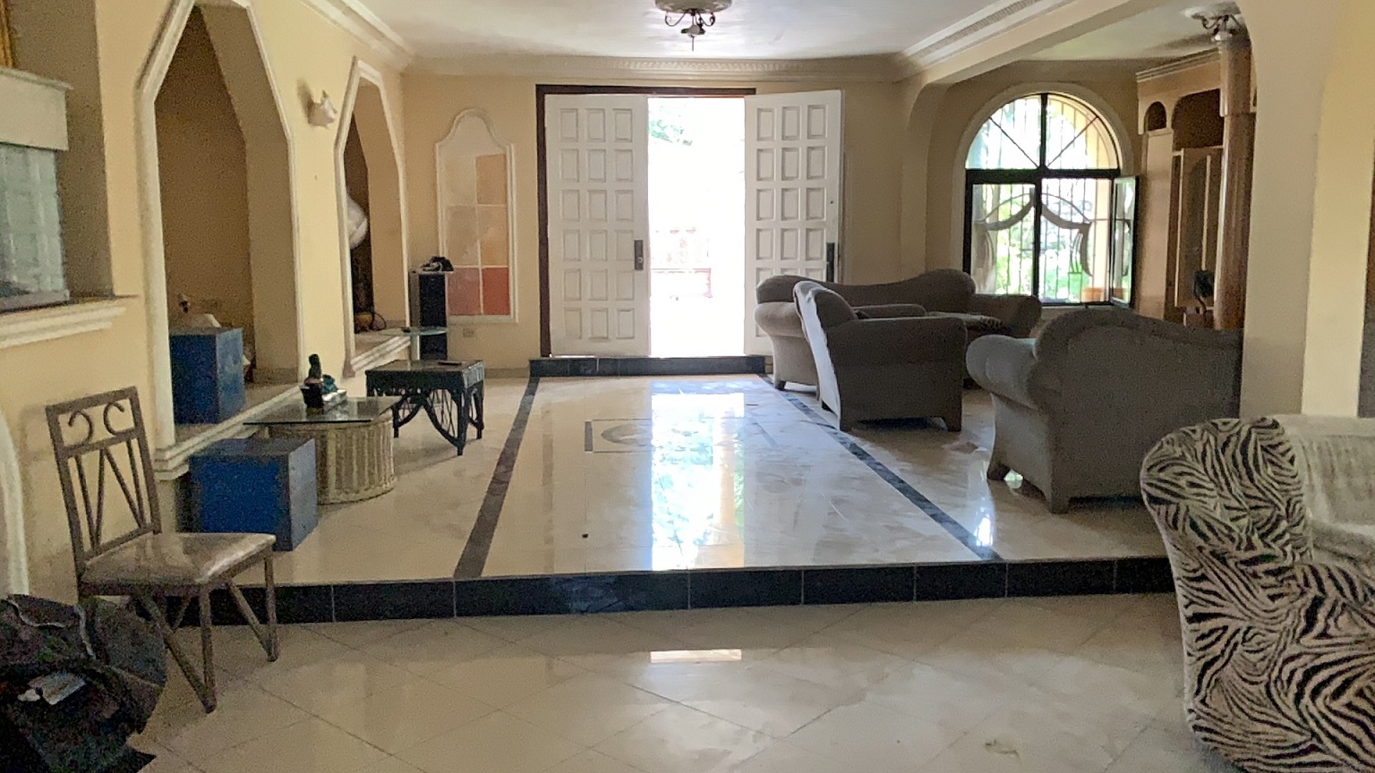 Palace-Style Villa for Sale, Vivy Mitchell, Petion-Ville, Haiti – House or Home has 6 Spacious Bedrooms, 5 1/2 Bathrooms, Multiple Grand Living & Dining Rooms, Majestic Kitchen, Whirlpool Jacuzzi Tub in Master Bedroom, Walk-in Closet, Basement Game Room & Gym, Floor-to-Ceiling Windows, Big Balconies, Terrace & Decks, Indoor & Outdoor Seating Areas, Ample Front-Back Yard Space, Reserved Space for Swimming Pool, Fruits, Vegetables, Tropical Trees, Two Gates, Brick Fence, Parking for 13+ Cars