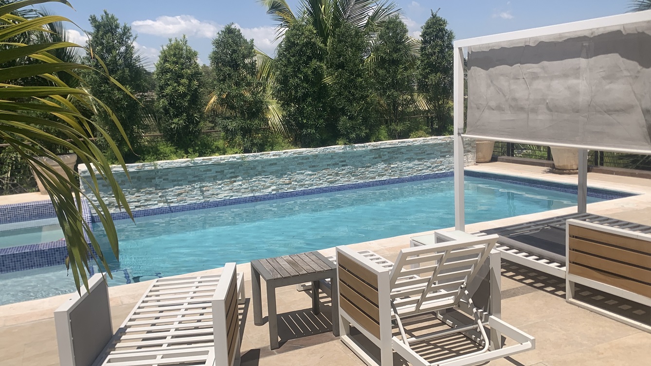 Lavish Furnished Paraseismic Mansion for Sale in Juvenat (Karibe Hotel Green Zone), Port-au-Prince, Haiti – 4 Spacious Bedrooms with Modern High-end Furniture & Appliances, Large Circular Living/Dining Rooms, 3 1/2 Stylish Bathrooms, Gourmet Kitchen, Panoramic Living/Dining Rooms, Gleaming Swimming Pool with Attached Jacuzzi, Multiple Seating Areas, Exclusive/Private Neighborhood, Robust 24/7 Solar-Powered Electricity System, Servant/Security Quarter