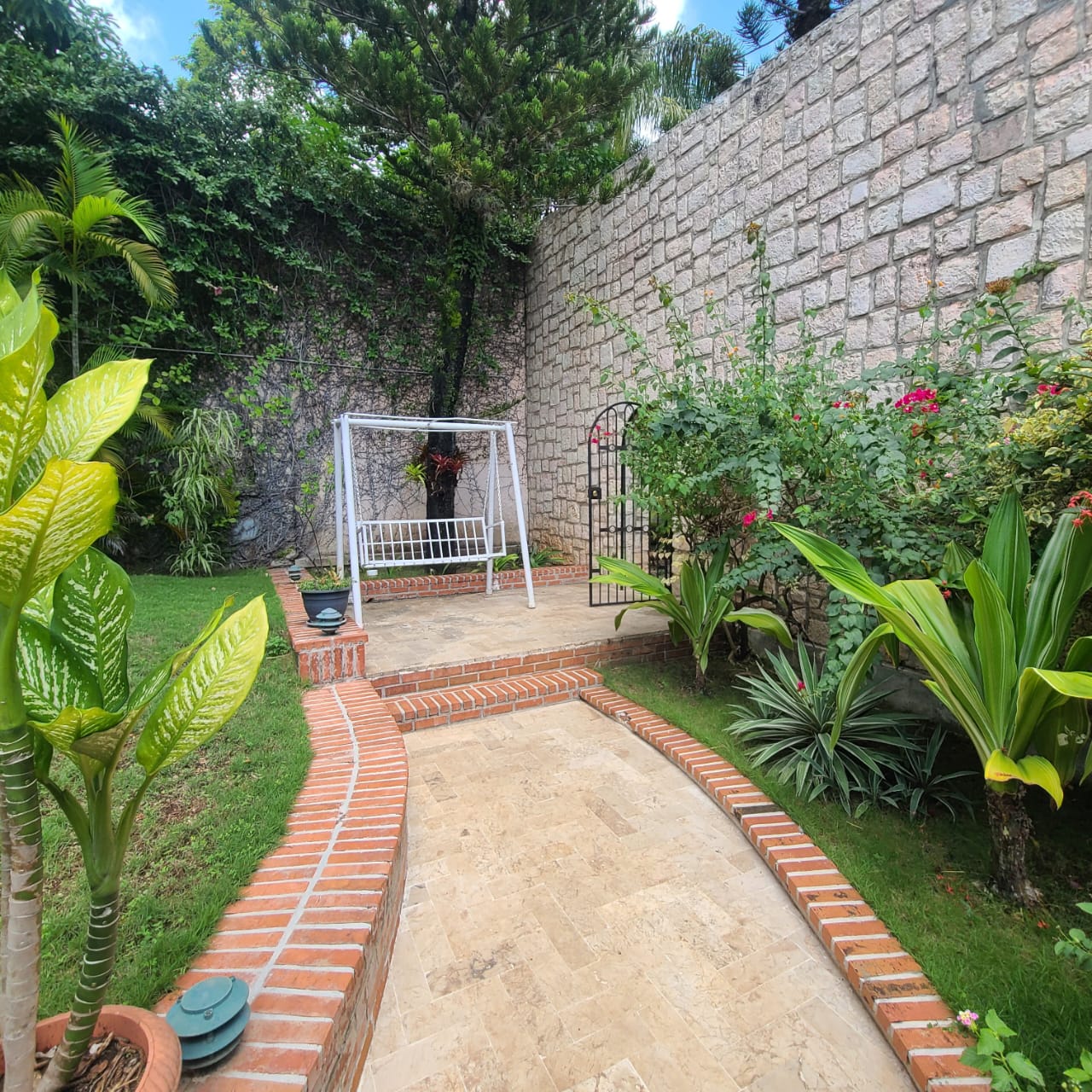Stunning Furnished House for SALE in Lower Morne Calvaire, Petion-Ville, Haiti – 3 Spacious Bedrooms with Modern High-end Furniture & Appliances, Capacious Living/Dining Rooms, 3 1/2 Stylish Bathrooms, Gourmet Kitchen, Panoramic Living/Dining Rooms, Radiant Swimming Pool with Chairs, Chaise Loungers, & Tables, Multiple Seating Areas, Exclusive/Private Neighborhood, Robust 24/7 Solar-Powered Electricity System, Servant/Security Quarters, Manicure, Lush Green Trees