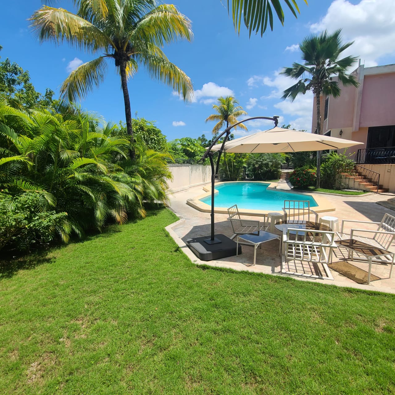 Stunning Furnished House for SALE in Lower Morne Calvaire, Petion-Ville, Haiti – 3 Spacious Bedrooms with Modern High-end Furniture & Appliances, Capacious Living/Dining Rooms, 3 1/2 Stylish Bathrooms, Gourmet Kitchen, Panoramic Living/Dining Rooms, Radiant Swimming Pool with Chairs, Chaise Loungers, & Tables, Multiple Seating Areas, Exclusive/Private Neighborhood, Robust 24/7 Solar-Powered Electricity System, Servant/Security Quarters, Manicure, Lush Green Trees