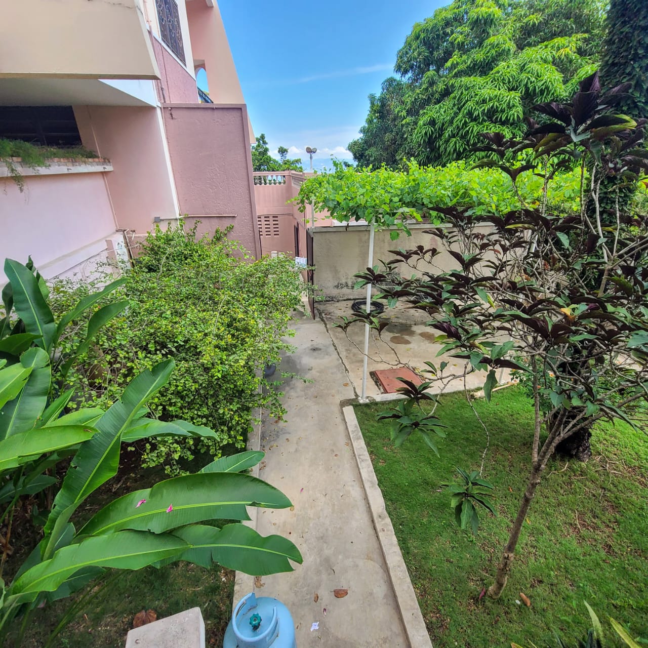 Stunning Furnished House for SALE in Lower Morne Calvaire, Petion-Ville, Haiti – 3 Spacious Bedrooms with Modern High-end Furniture & Appliances, Capacious Living/Dining Rooms, 3 1/2 Stylish Bathrooms, Gourmet Kitchen, Panoramic Living/Dining Rooms, Radiant Swimming Pool with Chairs, Chaise Loungers, & Tables, Multiple Seating Areas, Exclusive/Private Neighborhood, Robust 24/7 Solar-Powered Electricity System, Servant/Security Quarters, Manicure, Lush Green Trees