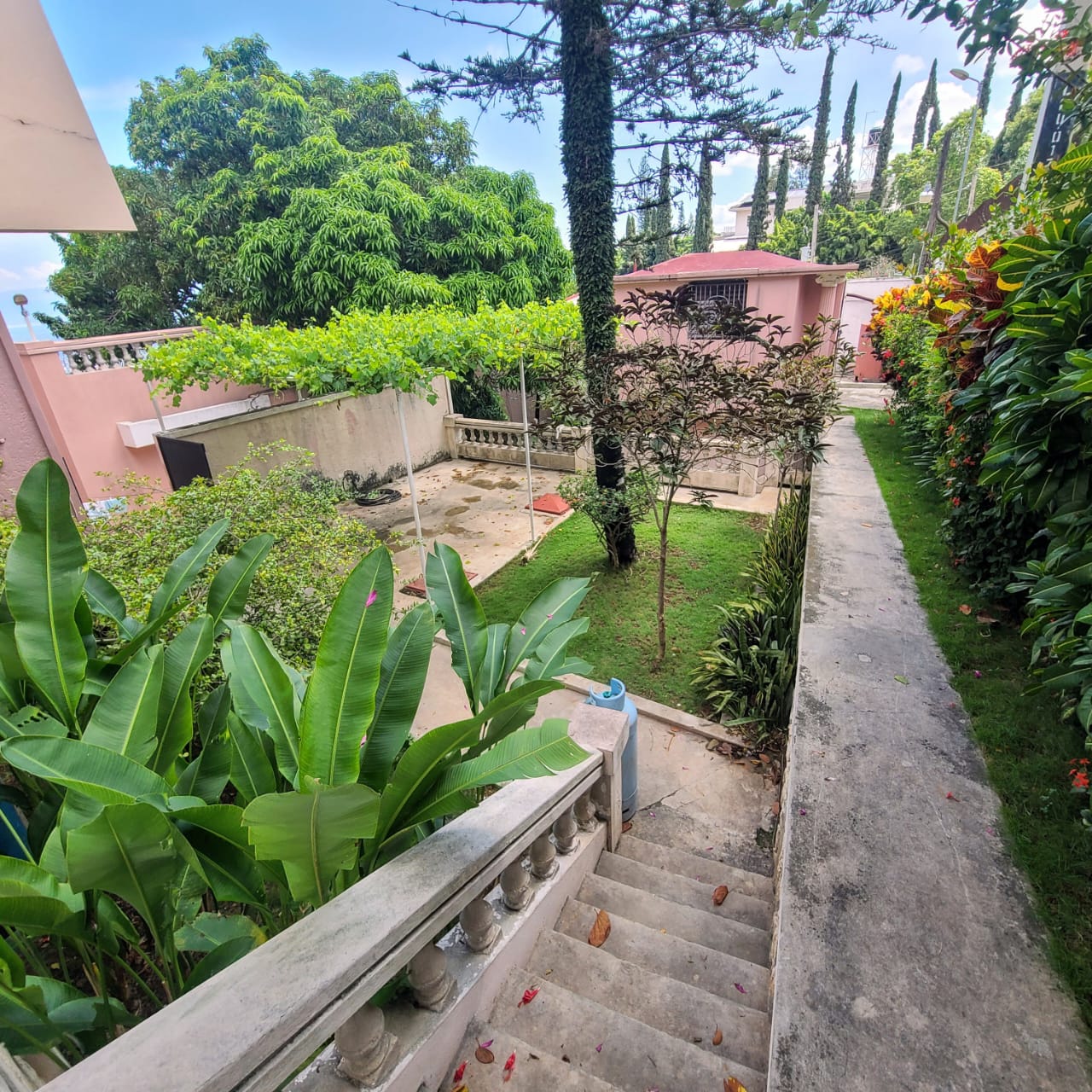 Stunning Furnished House for SALE in Lower Morne Calvaire, Petion-Ville, Haiti – 3 Spacious Bedrooms with Modern High-end Furniture & Appliances, Capacious Living/Dining Rooms, 3 1/2 Stylish Bathrooms, Gourmet Kitchen, Panoramic Living/Dining Rooms, Radiant Swimming Pool with Chairs, Chaise Loungers, & Tables, Multiple Seating Areas, Exclusive/Private Neighborhood, Robust 24/7 Solar-Powered Electricity System, Servant/Security Quarters, Manicure, Lush Green Trees