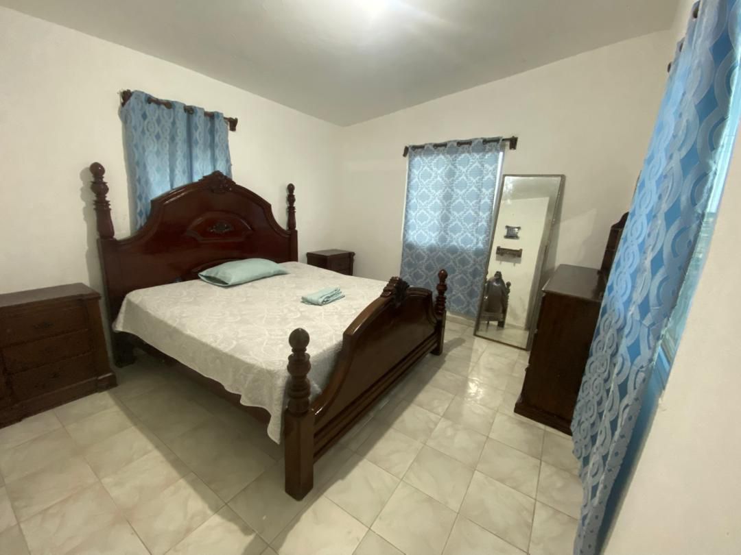 Move-in Ready Furnished Apartment for RENT in Petite Anse, Cap-Haïtien, Haiti – 2 Bedrooms, 1 Bathroom, Living/Dining Rooms with Clean Furniture & Appliances, Modern Kitchen, Large Upper Balcony with Views, Fans, Washer/Dryer, High-Speed Internet, Television (TV), Solar-Powered Electricity, Indoor Parking for 1 Car