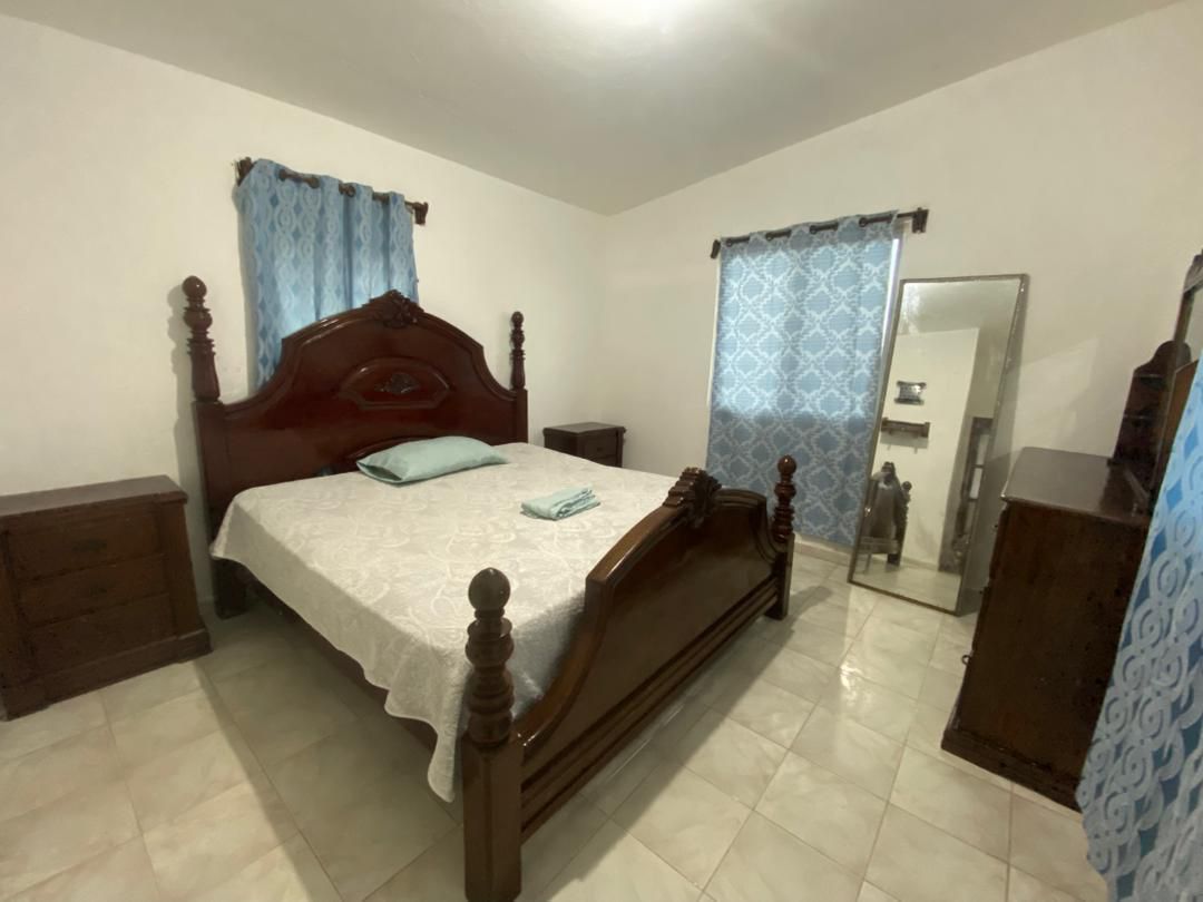 Move-in Ready Furnished Apartment for RENT in Petite Anse, Cap-Haïtien, Haiti – 2 Bedrooms, 1 Bathroom, Living/Dining Rooms with Clean Furniture & Appliances, Modern Kitchen, Large Upper Balcony with Views, Fans, Washer/Dryer, High-Speed Internet, Television (TV), Solar-Powered Electricity, Indoor Parking for 1 Car